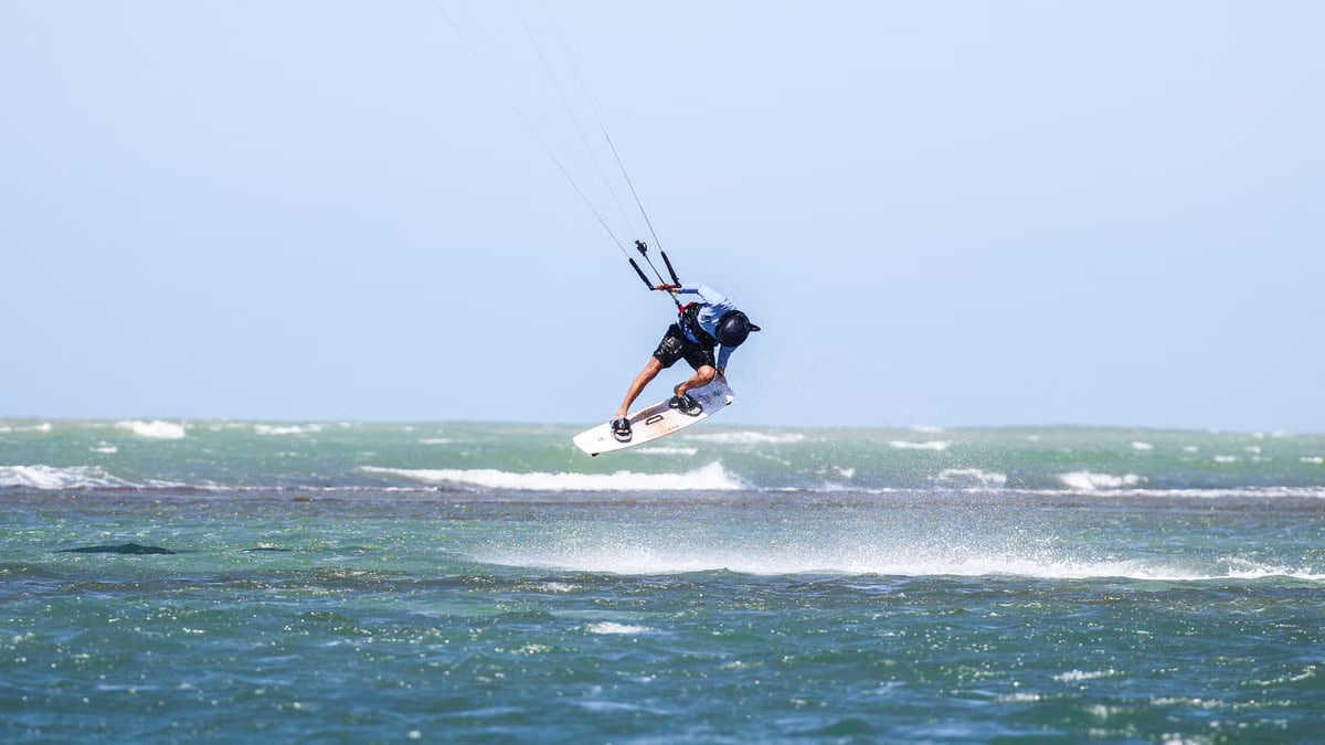 Dynamic kitesurfing action over ocean waves in Adicora, capturing the thrill of summer water sports.